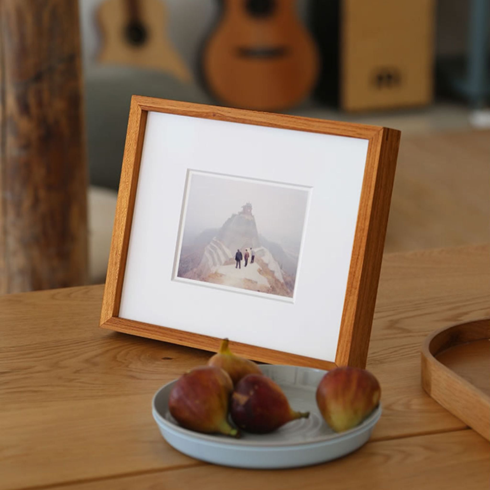Wooden photo frame with a small picture on a wooden table with fruits. Teak wood picture frame.