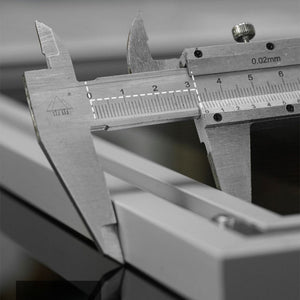Close-up of a vernier caliper measuring the aluminum alloy back frame on the LEGO Technic acrylic display board