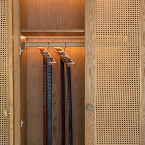 Wooden wardrobe with hanging belts and a textured door