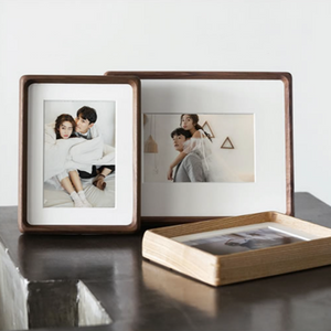 Two wooden photo frames with images of a couple on a reflective surface.