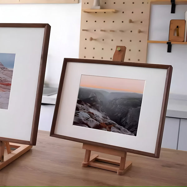 Framed landscape photo on a wooden stand with a pegboard in the background. Black walnut beveled picture frame. 