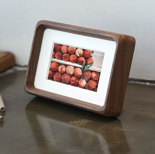 Black walnut wooden photo frame with a digital display showing images of peaches on a reflective surface.
