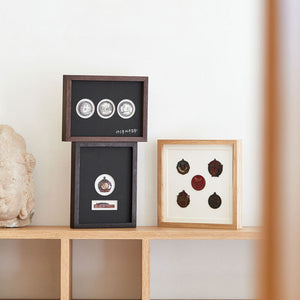 Framed decorative items on a wooden shelf against a white wall. Top to bottom, left to right:  black walnut, wenge, white ash wood.