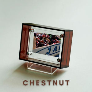 Brown acrylic picture frame with a reflective surface displaying 'J A' and 'CHESTNUT' text on a light gray background.