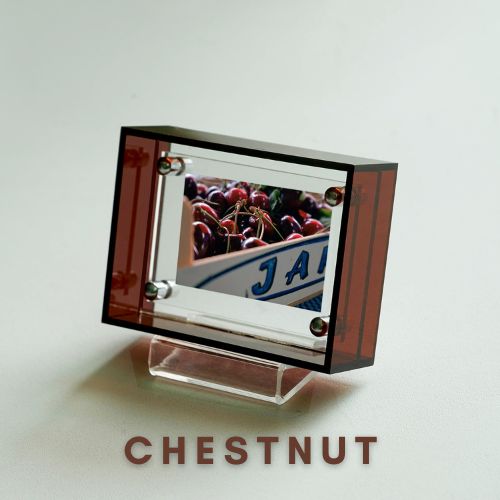 Brown acrylic picture frame with a reflective surface displaying 'J A' and 'CHESTNUT' text on a light gray background.