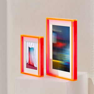 Electric pink thick acrylic picture frames on a white surface with a light gray background