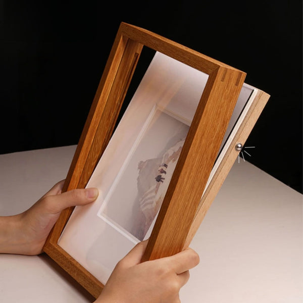 Wooden picture frame held open by a hand, revealing a small painting inside. Showing how to open the frame. 