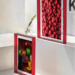 Two red acrylic framed artworks on a wall, one with fruit and the other with raspberries.