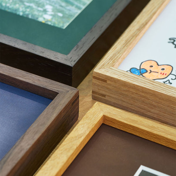 Close-up of wooden picture frames with different designs and colors. Teak, Wenge, Black Walnut, and White ash picture frames. 