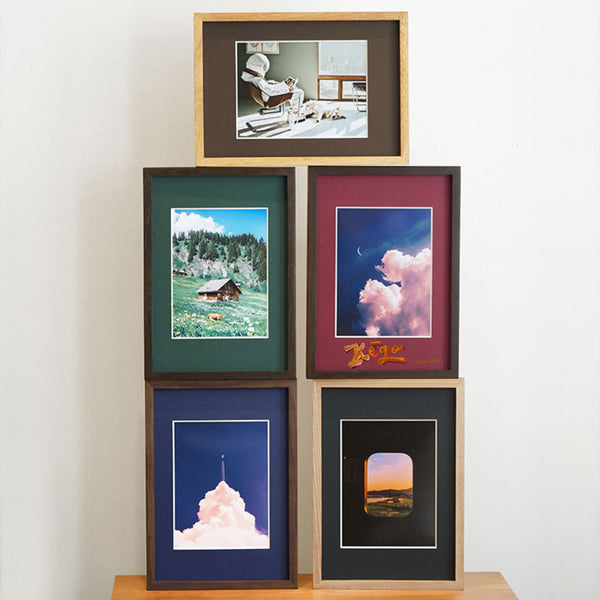 Collection of framed pictures on a wooden surface with a white background. Top to bottom, left to right, Teak, Wenge, Wenge, Black Walnut, White ash picture frames stacked together.