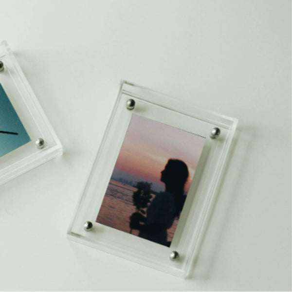 Clear acrylic photo frame with a silhouette of a couple at sunset on a white surface.