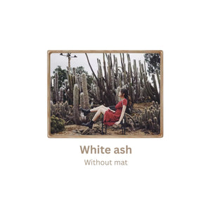 White ash wood-framed photograph of a person in a red dress sitting among cacti with 'White ash, without mat' frame text. 