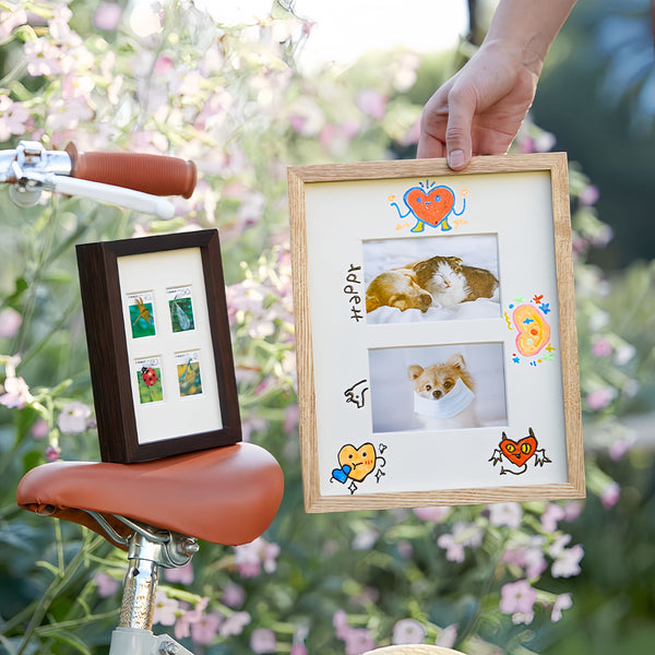 Person holding a wooden picture frame with a dog photo, sitting on a bicycle with another framed photo on the seat. White ash wood and black walnut frame. 