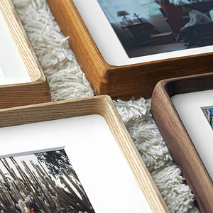 Close-up of wooden picture frames with photos inside on a textured surface.