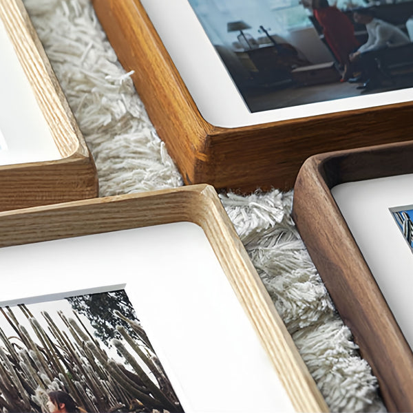 Close-up of wooden picture frames with photos inside on a textured surface.