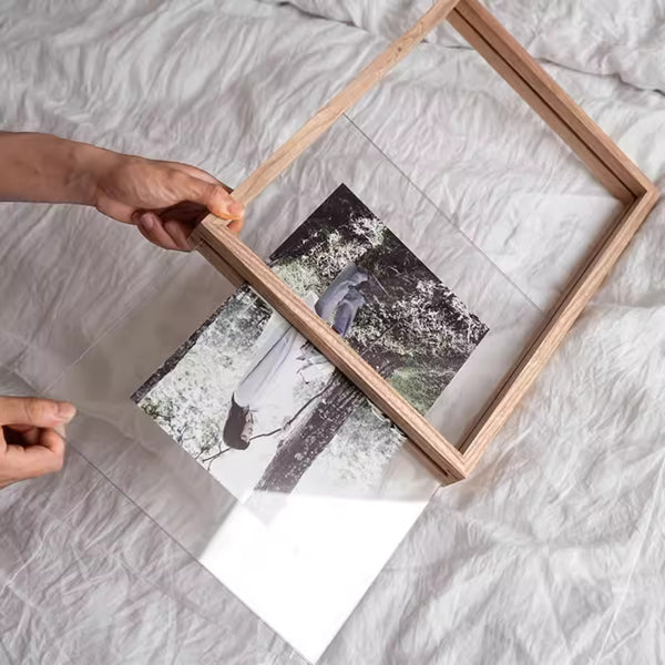 Person holding a White ash wood picture frame with a photograph inside on a light-colored surface.