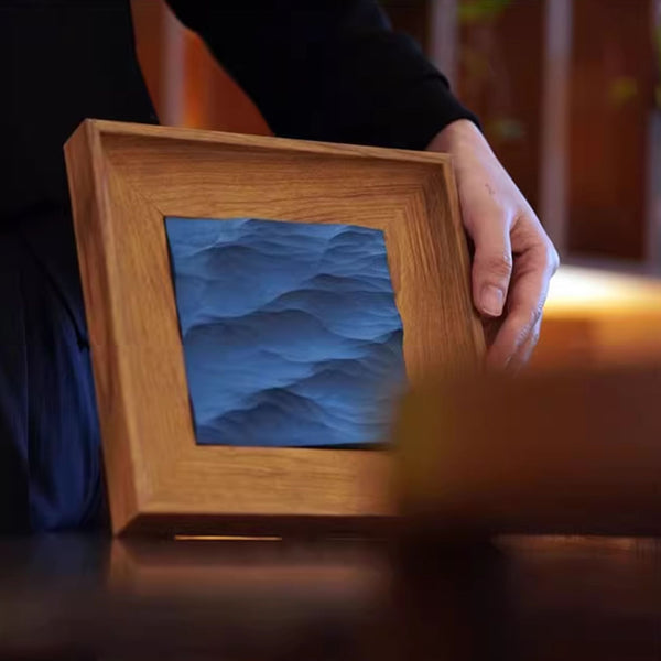 Wooden frame with a textured blue wave design held by a person