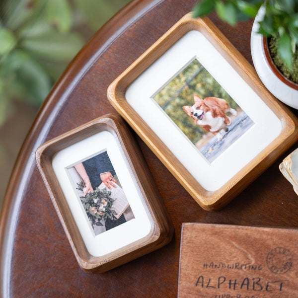 Two wooden picture frames on a wooden surface, with one containing a photo of a corgi dog.