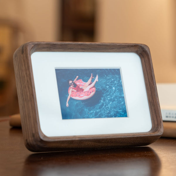 Wooden mini black walnut photo frame displaying a picture on a wooden surface. 3.5in x 5in. 