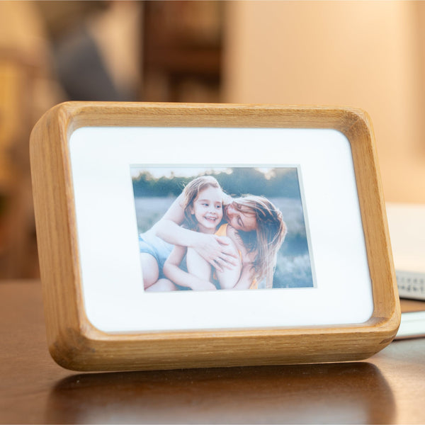Wooden mini teak photo frame displaying a picture on a wooden surface. 3.5in x 5in. 
