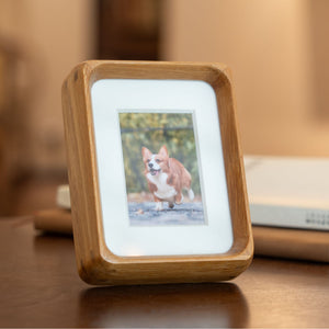 Wooden mini teak photo frame displaying a picture on a wooden surface. 3in x 4in. Polaroid fitting.
